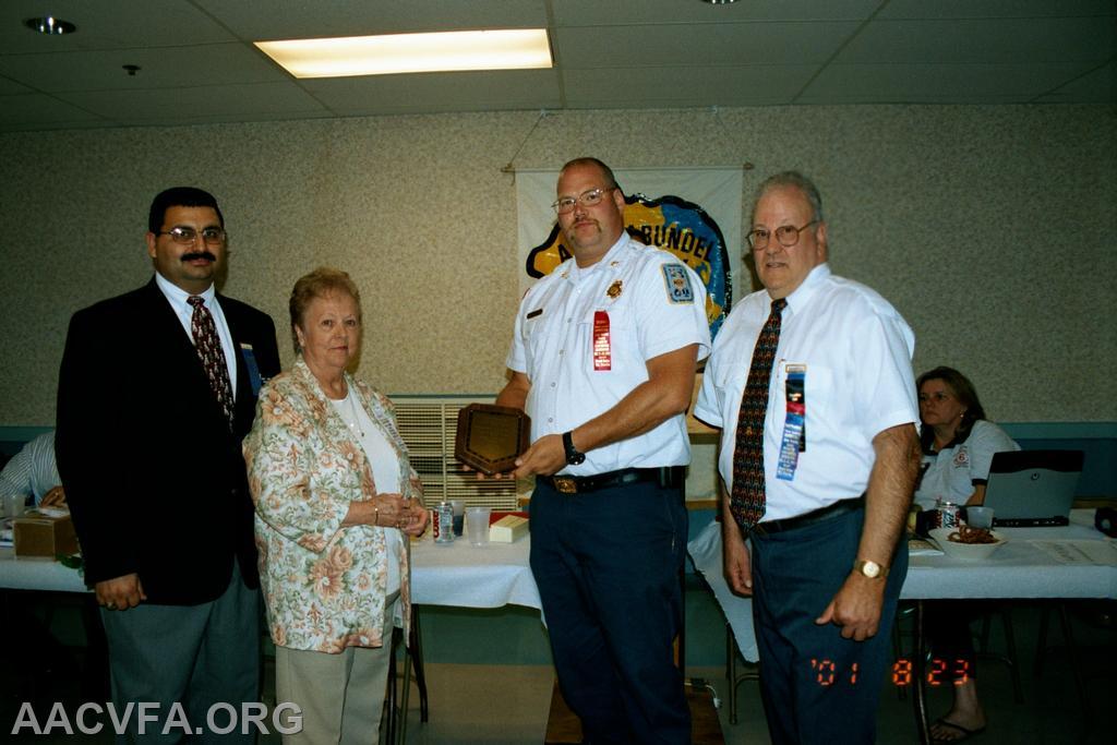 President John F. Long, Jr., Boot Raynor's widow, Earleigh Heights Asst. Chief Mike Sohn, Past President Bob Seibel. Jesse Fisher Award Plague.